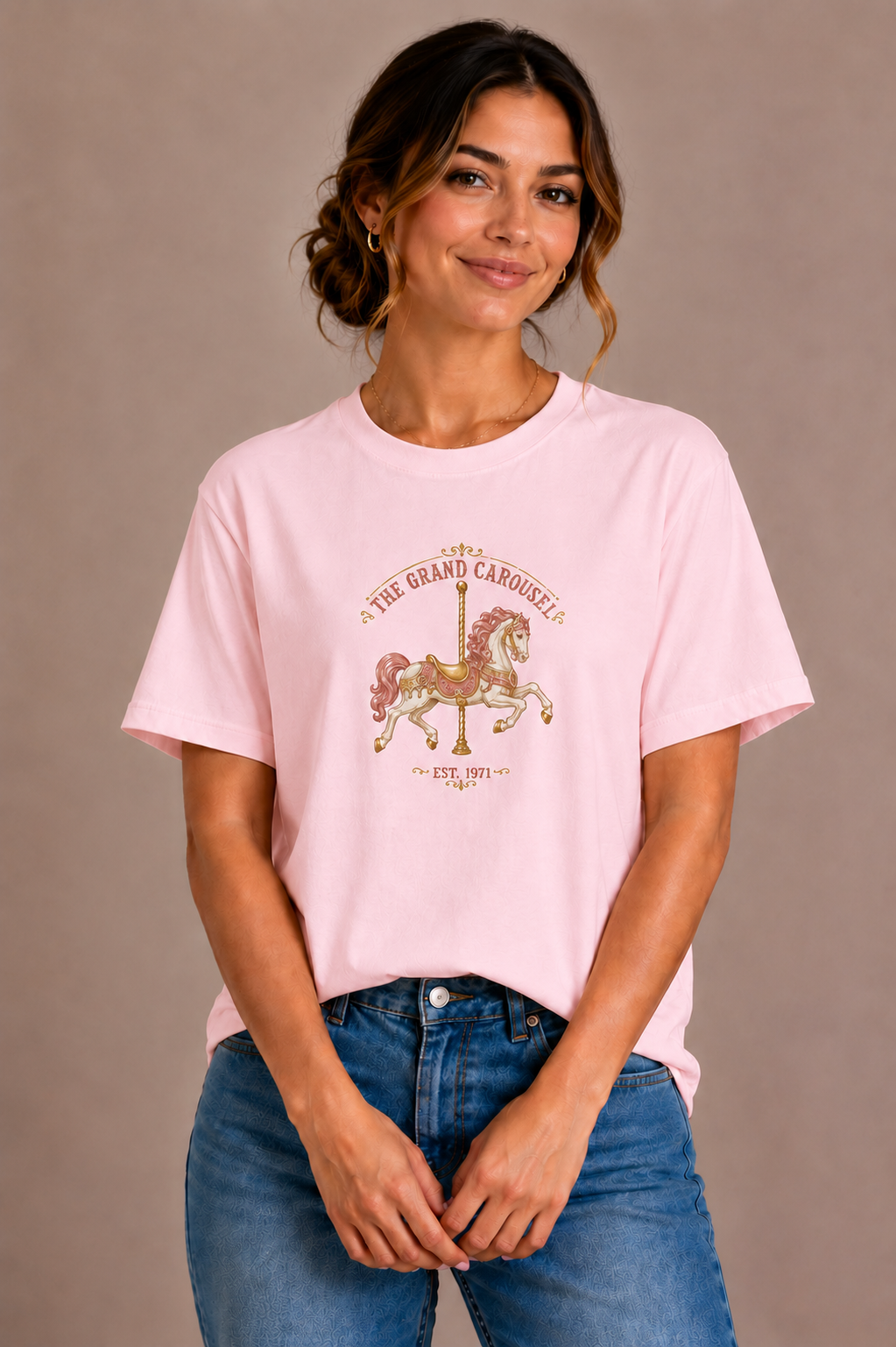 Woman wearing a pink crew-neck t-shirt with the 'The Grand Carousel Est. 1971' carousel horse design printed on the chest