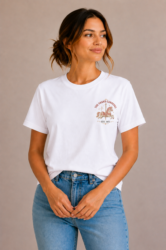 Woman wearing a white crew-neck t-shirt with the 'The Grand Carousel Est. 1971' carousel horse design printed small on the chest
