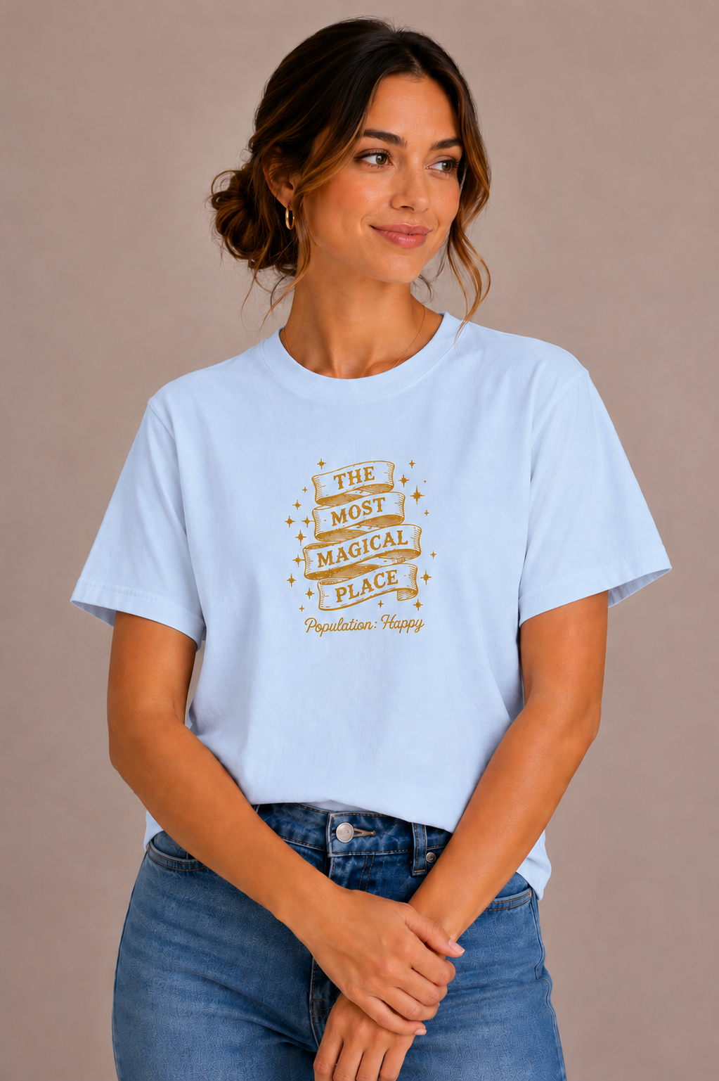 Woman wearing a blue crew-neck t-shirt with the 'The Most Magical Place – Population: Happy' ribbon banner design printed on the chest