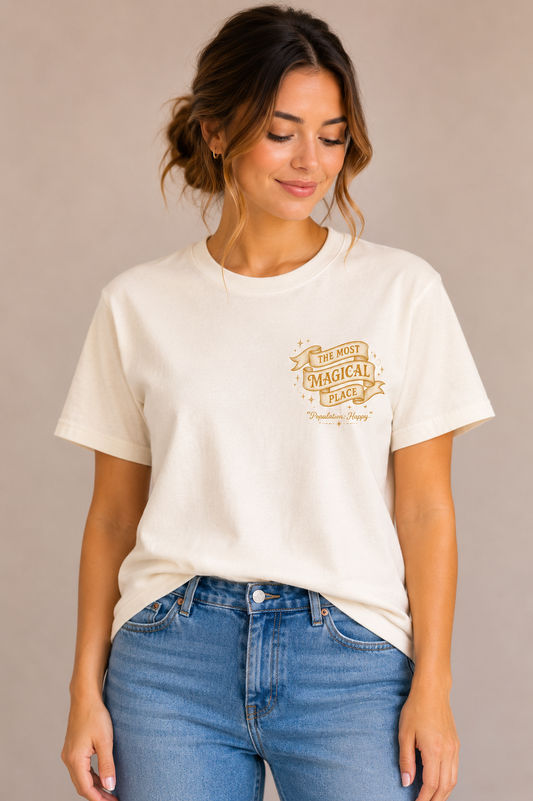 Woman wearing a sand crew-neck t-shirt with the 'The Most Magical Place – Population: Happy' ribbon banner design printed on the chest